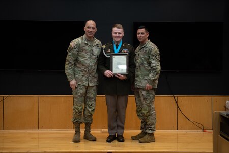 People stand in Army uniform on a stage.