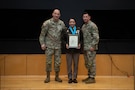 People stand in Army uniform on a stage.