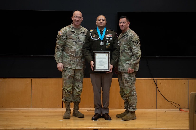 People stand in Army uniform on a stage.