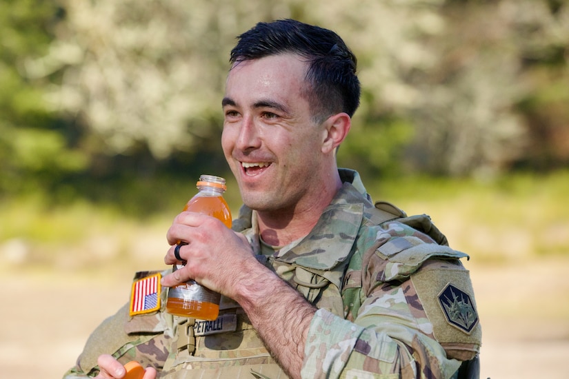Soldier drinking an orange beverage filled with electrolytes.