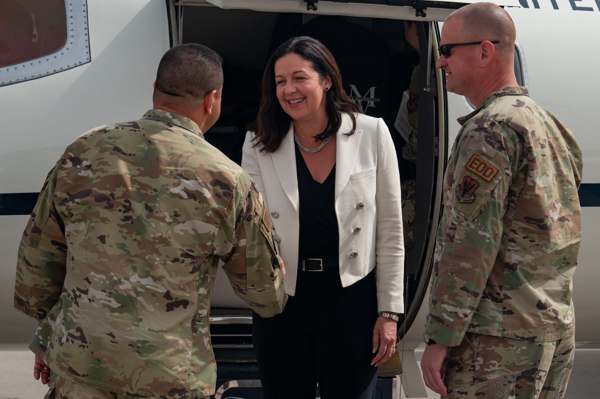 U.S. Air Force Chief Master Sgt. Lester Largaespada, left, 99th Air Base Wing command chief and Col. Joshua DeMotts, 99th ABW commander, greets the Hon. Kristyn Jones, assistant secretary of the Air Force for Financial Management and Comptroller, performing the duties of under secretary of the Air Force before her tour of Nellis Air Force Base, April 7, 2023.