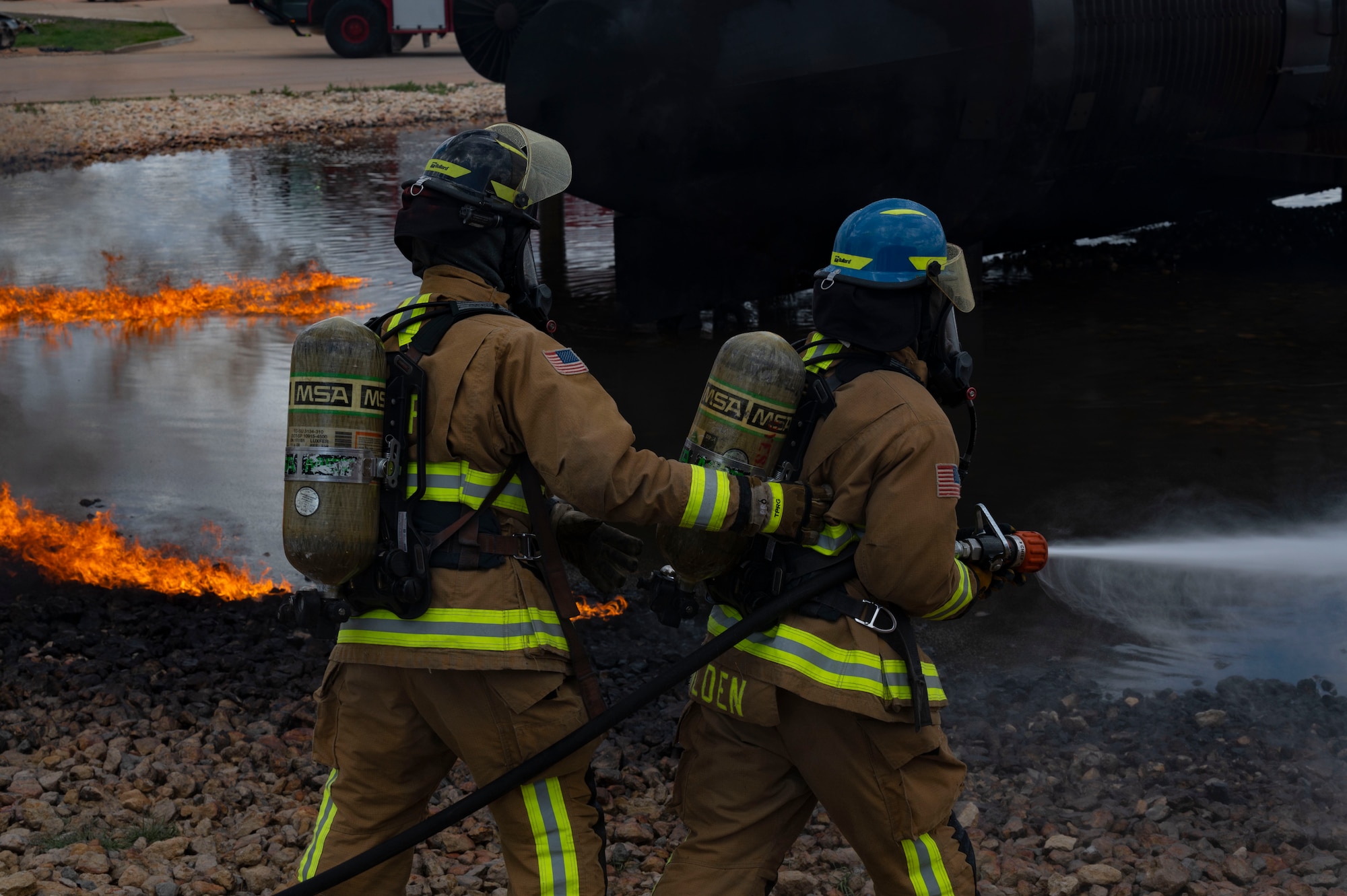 Firefighters from the 7th Civil Engineering Squadron extinguish a fire during a live fire drill on Dyess Air Force Base, Texas, April 10, 2023. Firefighters from the 7th CES trained with Dallas Fort Worth and Abilene firefighters to educate them on effectively using Ultra High-Pressure systems to extinguish fires in minimal time. The training was held to not only educate civilian firefighters on Ultra High-Pressure systems but also to strengthen the partnership with local and state fire departments. (U.S. Air Force photo by Airman Emma Anderson)