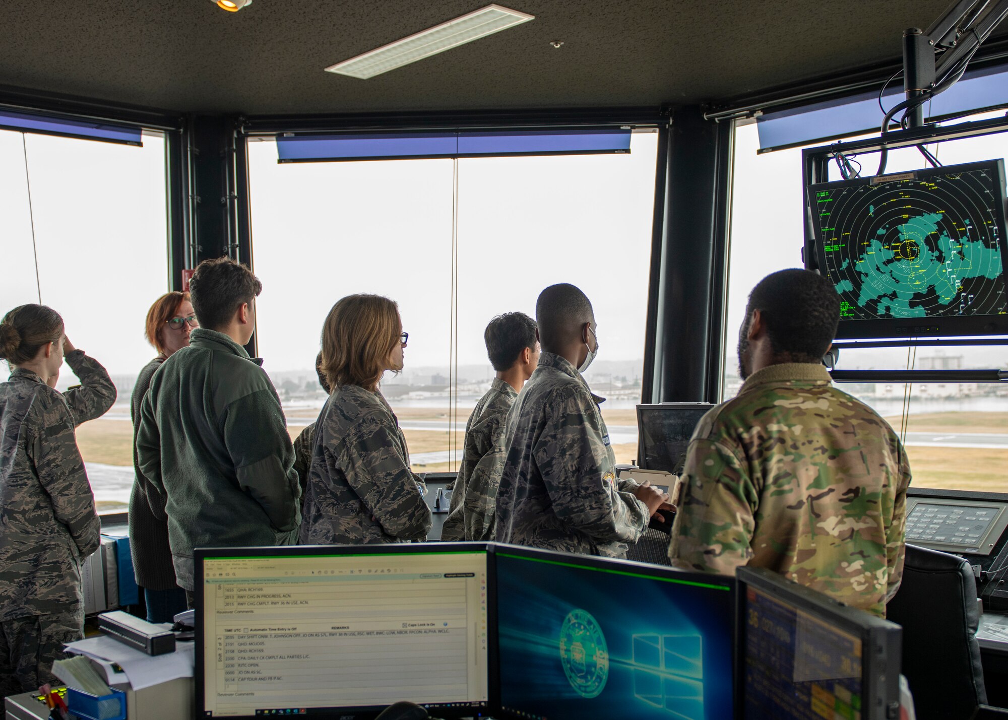 a soldier points out landmarks for a crowd of kids from the window of an air traffic control tower