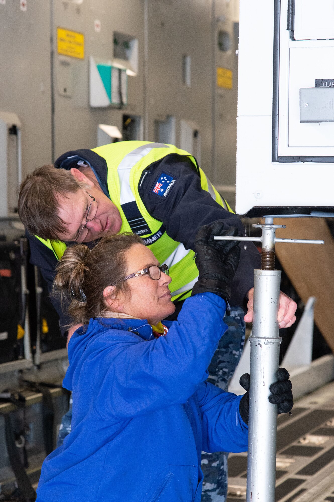 Royal Australian Air Force Squadron Leader Stephen Grimmer, assigned to the Persistent Maritime Unmanned Aircraft Systems Program Office (PMA-262) Triton – Cooperative Program out of Naval Air Station Patuxent River, Maryland, and Teresa Ruleman, Dayton T. Brown Inc. electrical engineer, attach a support to a Mobile Remote Quick Look trailer aboard a C-17 Globemaster III at Dover Air Force Base, Delaware, Feb. 1, 2023. The RQL trailer was flown to Andersen AFB, Guam by a 3rd Airlift Squadron aircrew. (U.S. Air Force photo by Roland Balik)