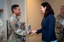 Man in uniform shakes hands with woman in suit