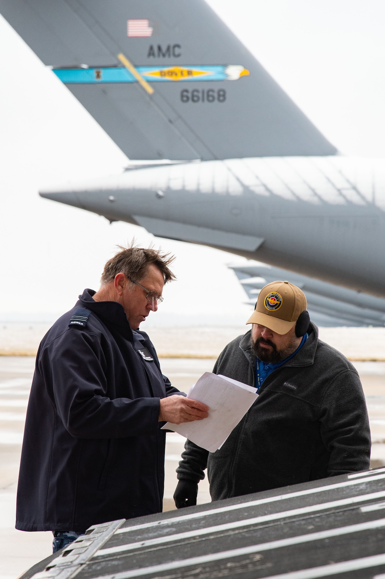 Royal Australian Air Force Squadron Leader Stephen Grimmer, left, and Matthew Buttrey, right, both assigned to the Persistent Maritime Unmanned Aircraft Systems Program Office (PMA-262) Triton – Cooperative Program out of Naval Air Station Patuxent River, Maryland, review cargo shipping documents at Dover Air Force Base, Delaware, Feb. 1, 2023. Grimmer and Buttrey are the Integrated Product Team Lead and co-lead, respectively, for the Ground Segment Execution for PMA-262 MQ-4C Triton Persistent Maritime Unmanned Aerial System Production IPT. (U.S. Air Force photo by Roland Balik)