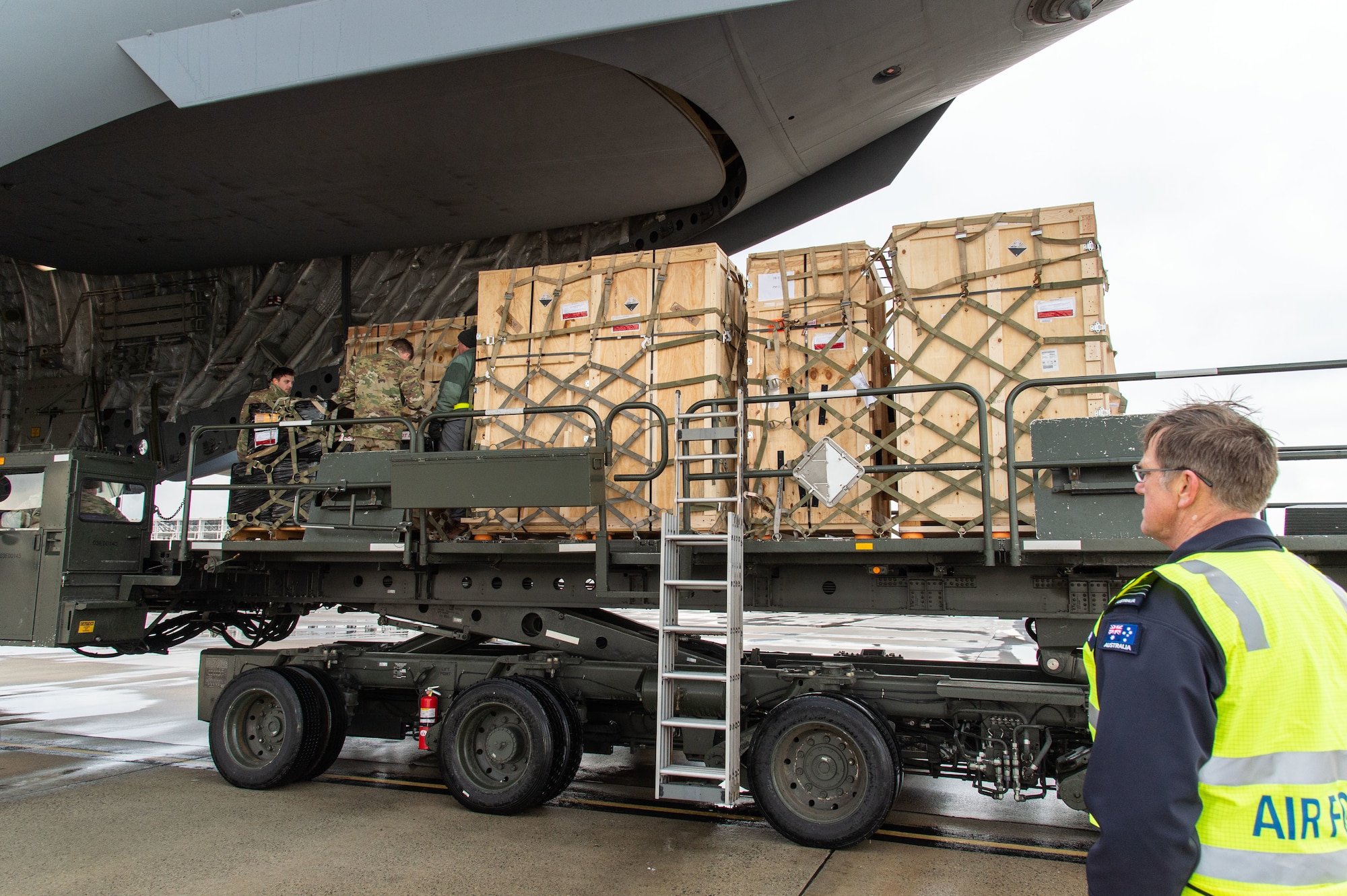 Royal Australian Air Force Squadron Leader Stephen Grimmer, assigned to the Persistent Maritime Unmanned Aircraft Systems Program Office (PMA-262) Triton – Cooperative Program out of Naval Air Station Patuxent River, Maryland, watches Forward Operating Base equipment being loaded onto a C-17 Globemaster III by 436th Aerial Port Squadron personnel at Dover Air Force Base, Delaware, Feb. 1, 2023. The FOB equipment and a Mobile Remote Quick Look trailer was flown to Andersen AFB, Guam, by a 3rd Airlift Squadron aircrew. (U.S. Air Force photo by Roland Balik)