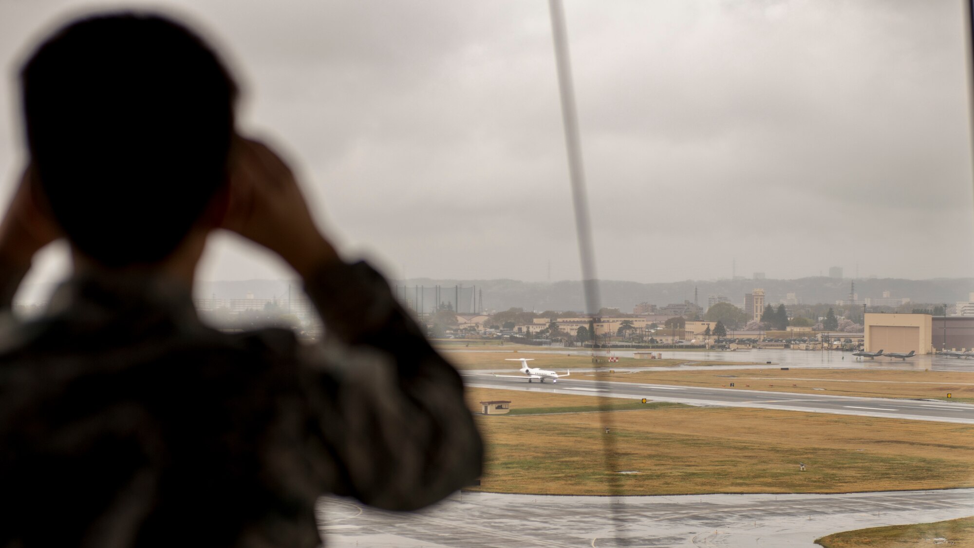 a kid with binoculars watches a small jet take off