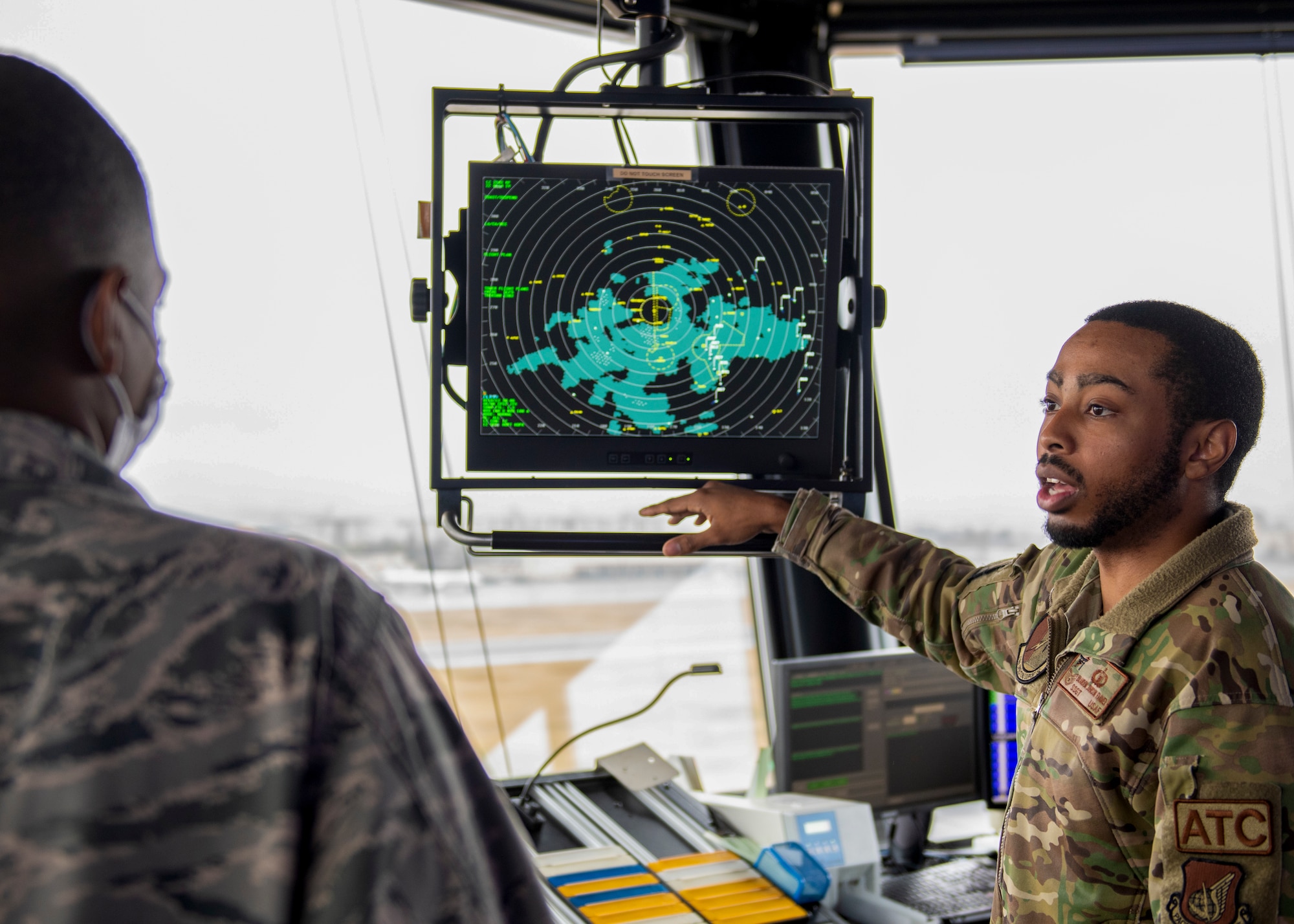 a soldier points at a tv displaying a radar map