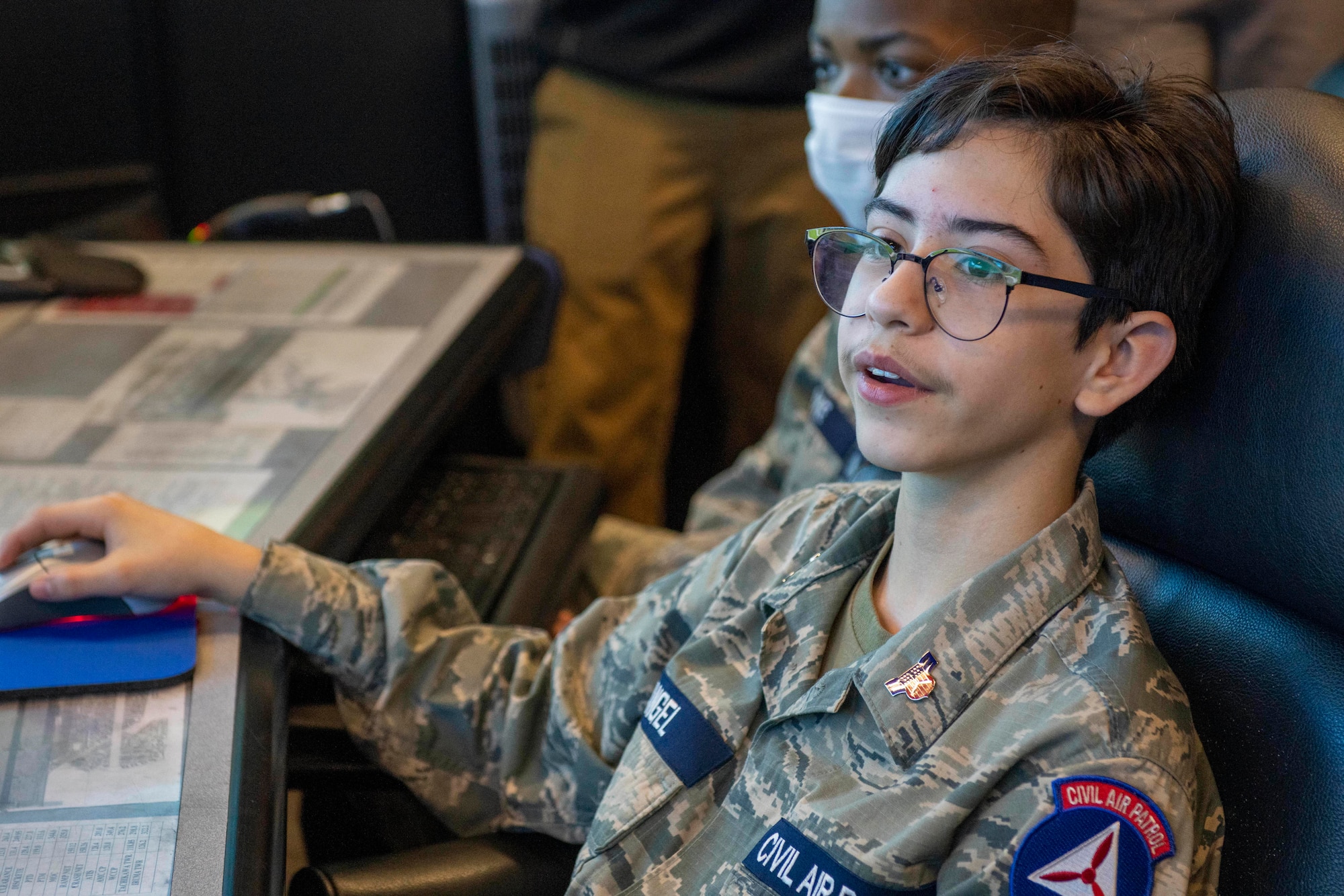 a cadet operates a computer while looking at a large screen