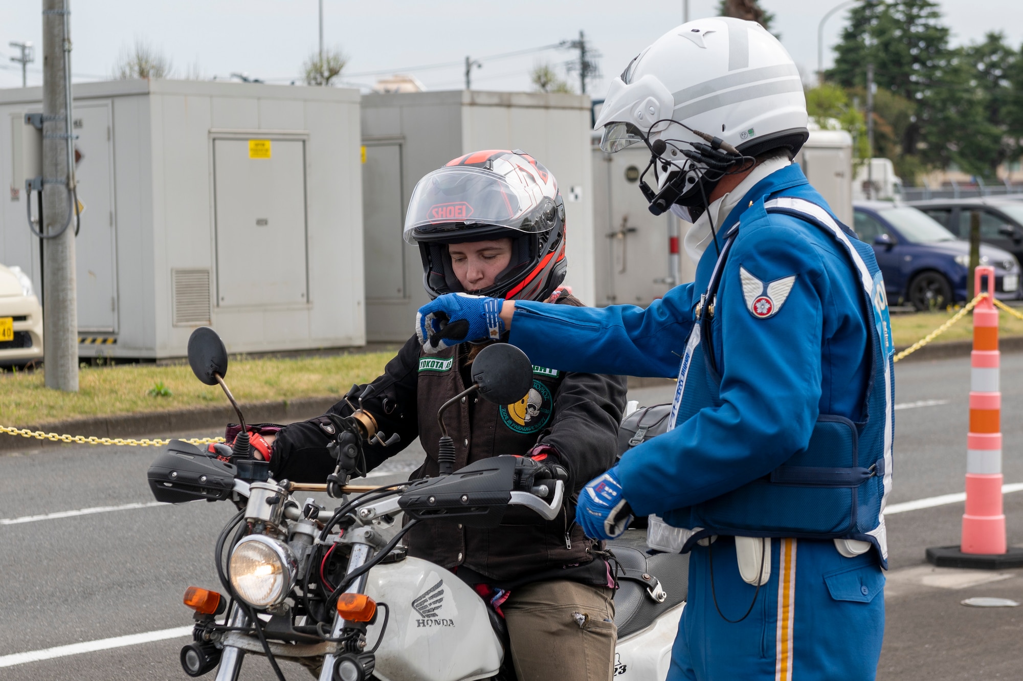 A police officer points the handlebars of a motorcycle a helmeted woman is riding