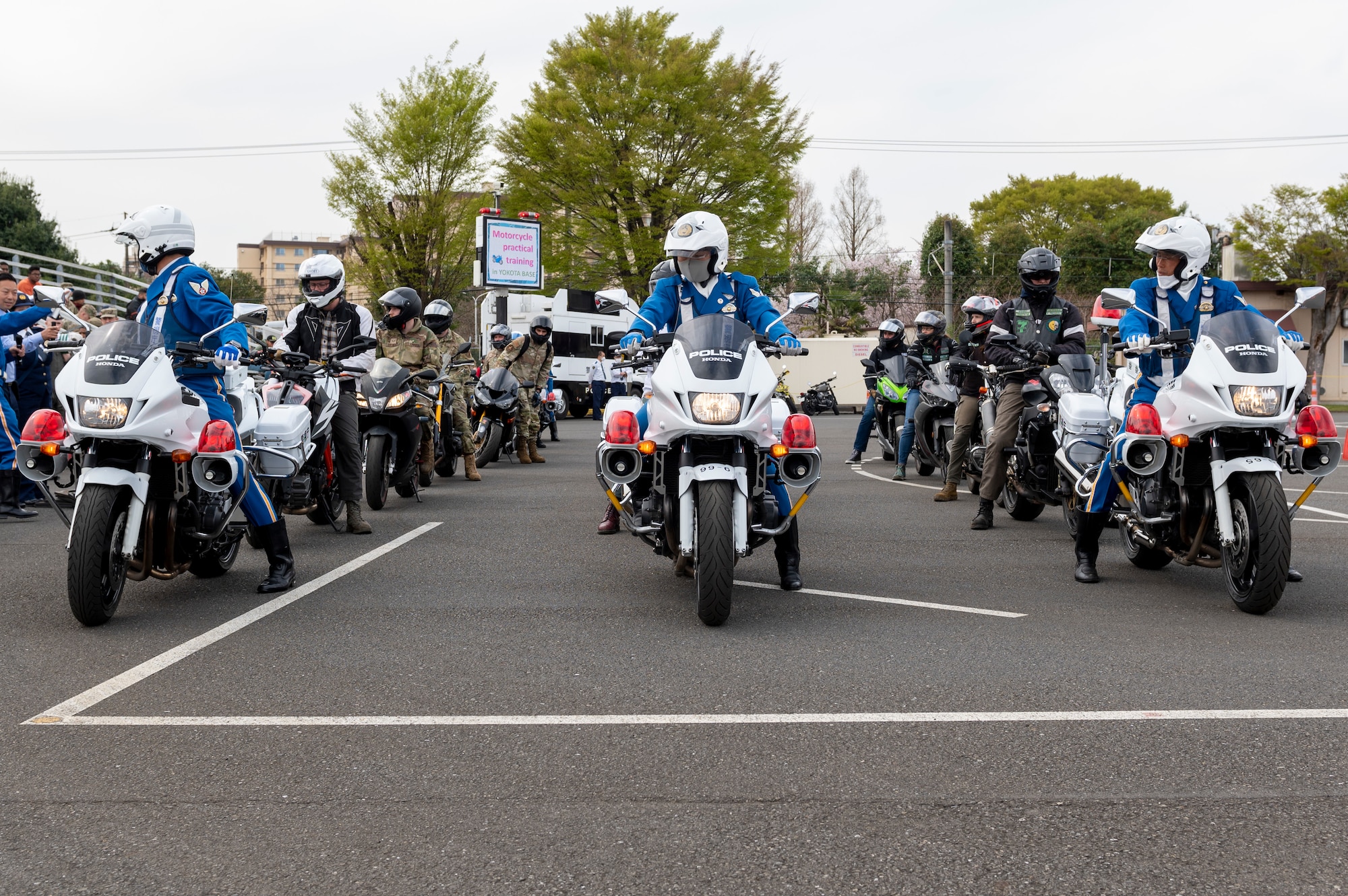 three rows of motorcycle riders stand waiting