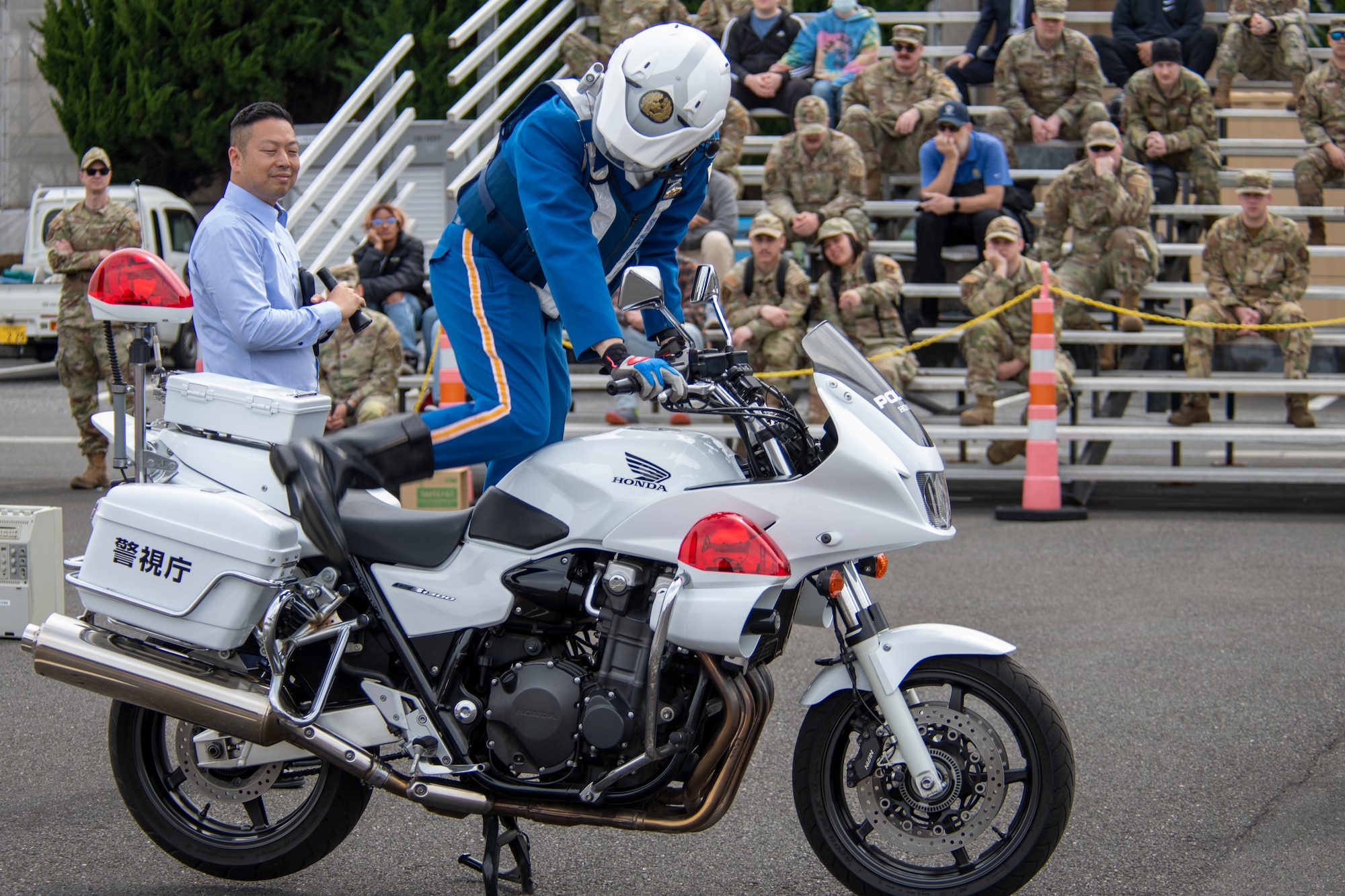 a policeman climbs aboard a motorcycle in front of a crowd
