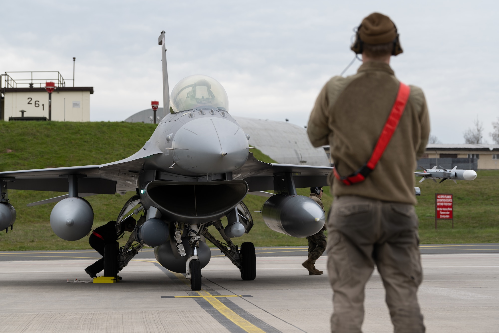 A jet on the flight line with a maintainer in the foreground.