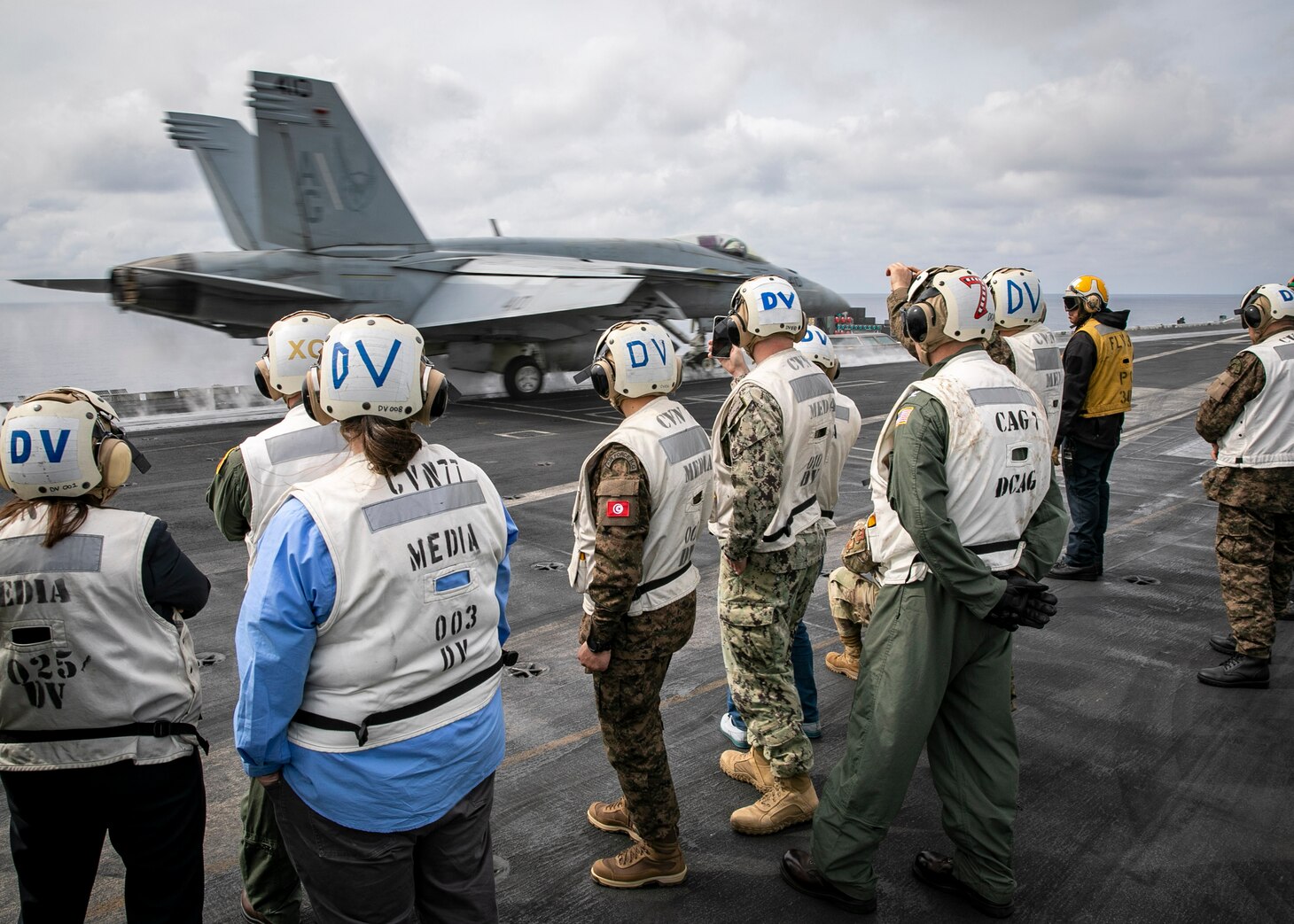 TYRRHENIAN SEA (March 22, 2023) Distinguished visitors watch an F/A-18E Super Hornet aircraft, attached to Strike Fighter Squadron (VFA) 136, launch from the flight deck of the Nimitz-class aircraft carrier USS George H.W. Bush (CVN 77), March 22, 2023. Carrier Air Wing (CVW) 7 is the offensive air and strike component of Carrier Strike Group (CSG) 10 and the George H.W. Bush CSG. The squadrons of CVW-7 are VFA-143, VFA-103, VFA-86, VFA-136, Carrier Airborne Early Warning Squadron (VAW) 121, Electronic Attack Squadron (VAQ) 140, Helicopter Sea Combat Squadron (HSC) 5, and Helicopter Maritime Strike Squadron (HSM) 46. The George H.W. Bush CSG is on a scheduled deployment in the U.S. Naval Forces Europe area of operations, employed by U.S. Sixth Fleet to defend U.S., allied and partner interests.