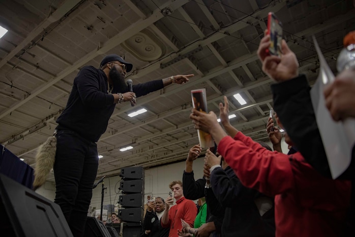 TYRRHENIAN SEA (March 25, 2023) Blanco Brown, performing artist, performs for Sailors aboard the Nimitz-class aircraft carrier USS George H.W. Bush (CVN 77) during a USO concert in the hangar bay, March 25, 2023. The George H.W. Bush Carrier Strike Group is on a scheduled deployment in the U.S. Naval Forces Europe area of operations, employed by U.S. Sixth Fleet to defend U.S., allied and partner interests.