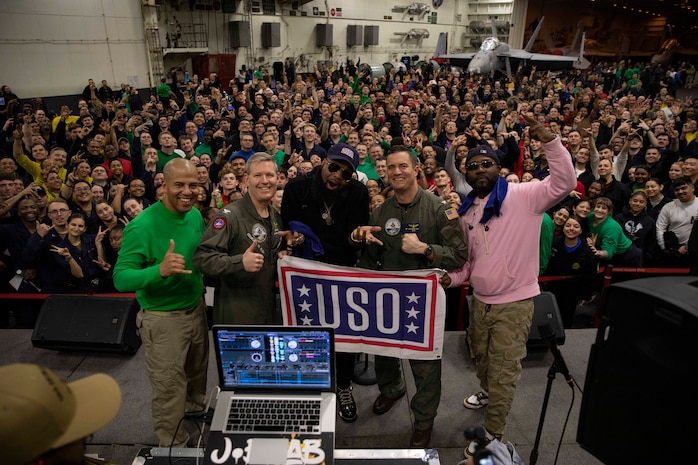 TYRRHENIAN SEA (March 25, 2023) Blanco Brown, center, poses for a photo with Capt. Dave Pollard, commanding officer of the Nimitz-class aircraft carrier USS George H.W. Bush (CVN 77), Capt. Nicholas DeLeo, executive officer and Command Master Chief Nicholas Wallace during a USO concert, March 25, 2023. The George H.W. Bush Carrier Strike Group is on a scheduled deployment in the U.S. Naval Forces Europe area of operations, employed by U.S. Sixth Fleet to defend U.S., allied and partner interests.