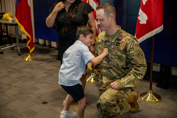 Son of U.S. Army Corps of Engineers Galveston District Deputy Commander for Mega Projects Lt. Col. Ian O’Sullivan places his father’s new rank insignia on his uniform during his promotion ceremony at the district headquarters.