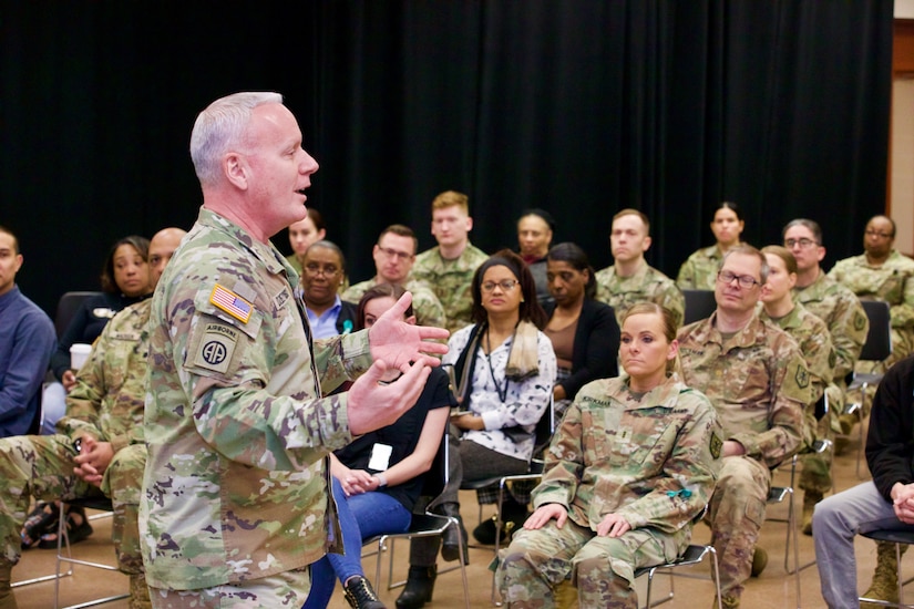 A Soldier speaks to a crowd of individuals in a room.