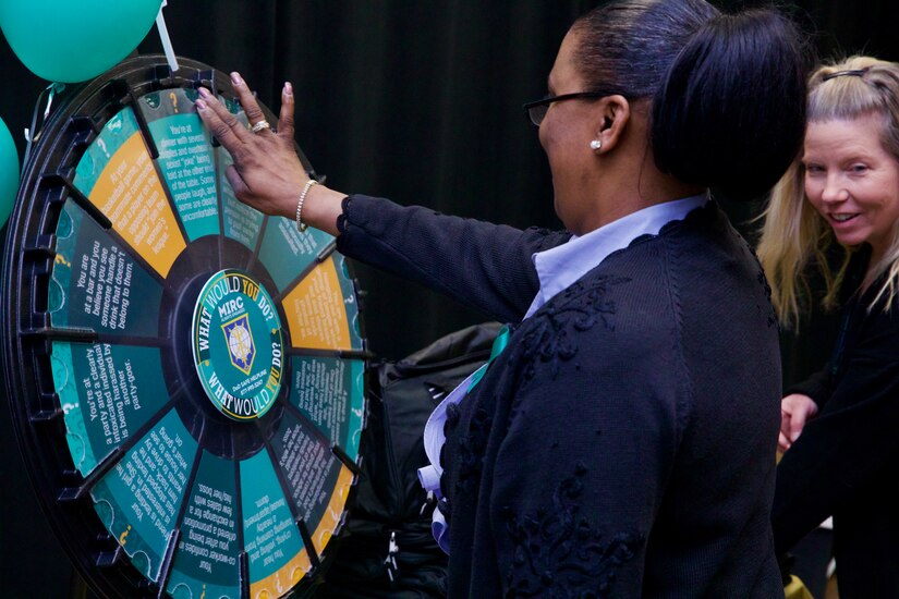 A woman spins a game wheel.