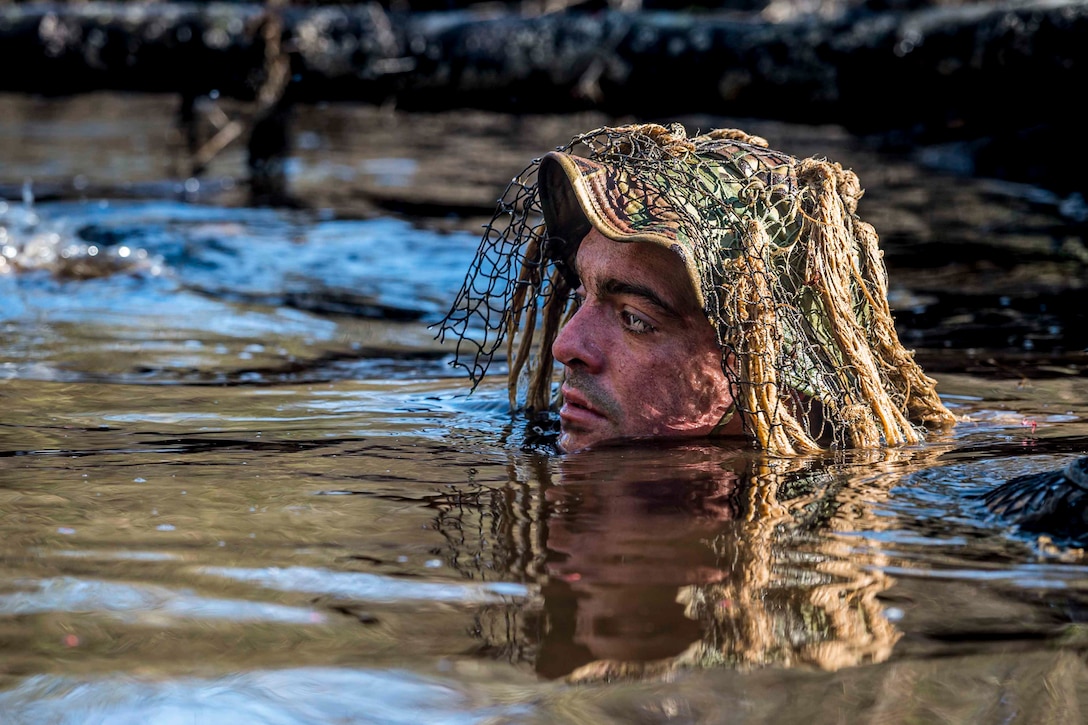 A soldier wearing a hat pops his head above water.