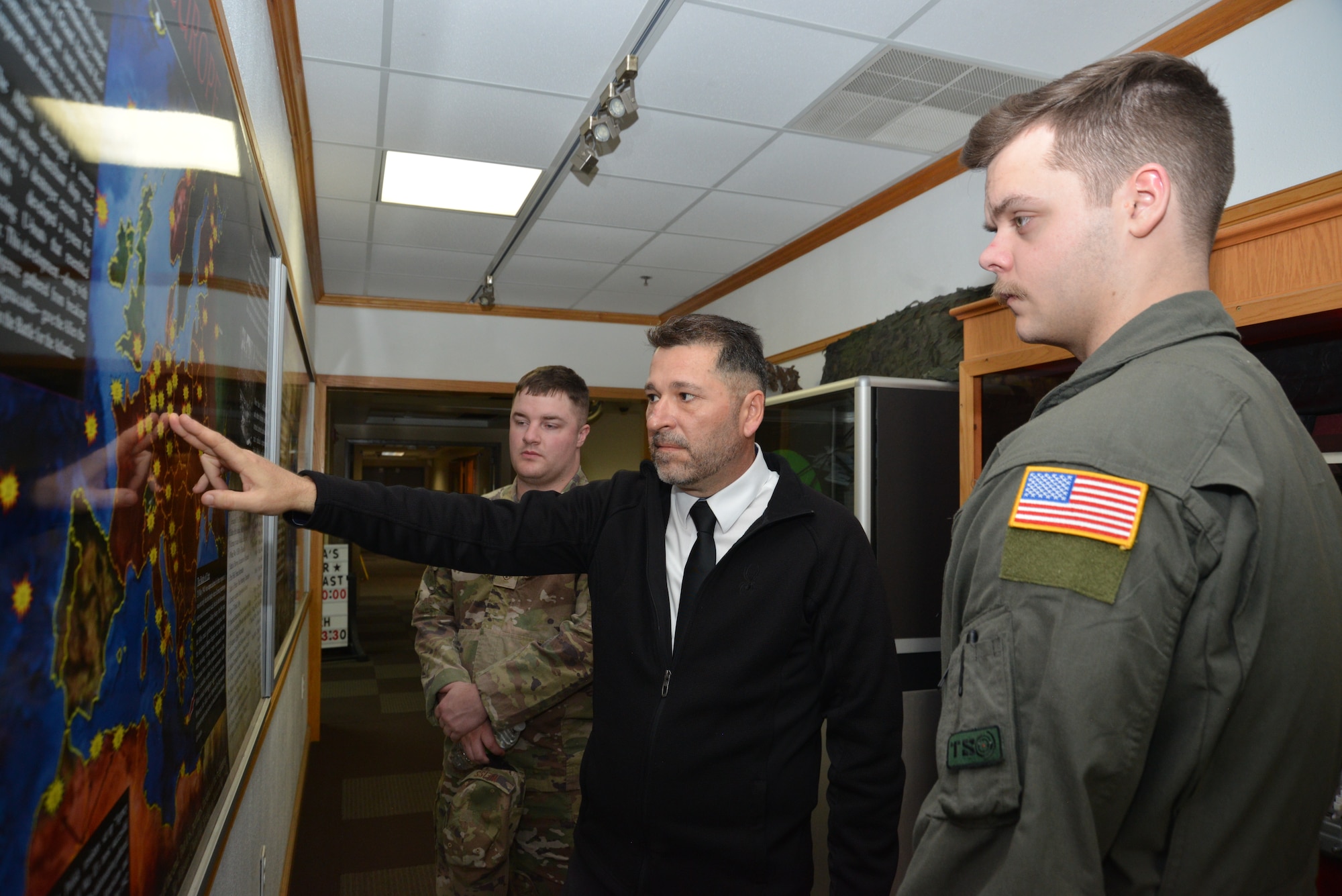 BJ Jones (middle) 16th Air Force historian and museum curator, explains a World War II graphic to Staff Sgt. Cole Weiss (left) tactical systems operator instructor from the 306th Intelligence Squadron and Staff Sgt. Gabriel Gibson, TSO instructor, 306th IS, March 29, 2023, in the Dennis F. Casey Heritage Center, at the 16th Air Force Headquarters building, Joint Base San Antonio-Lackland, Texas.