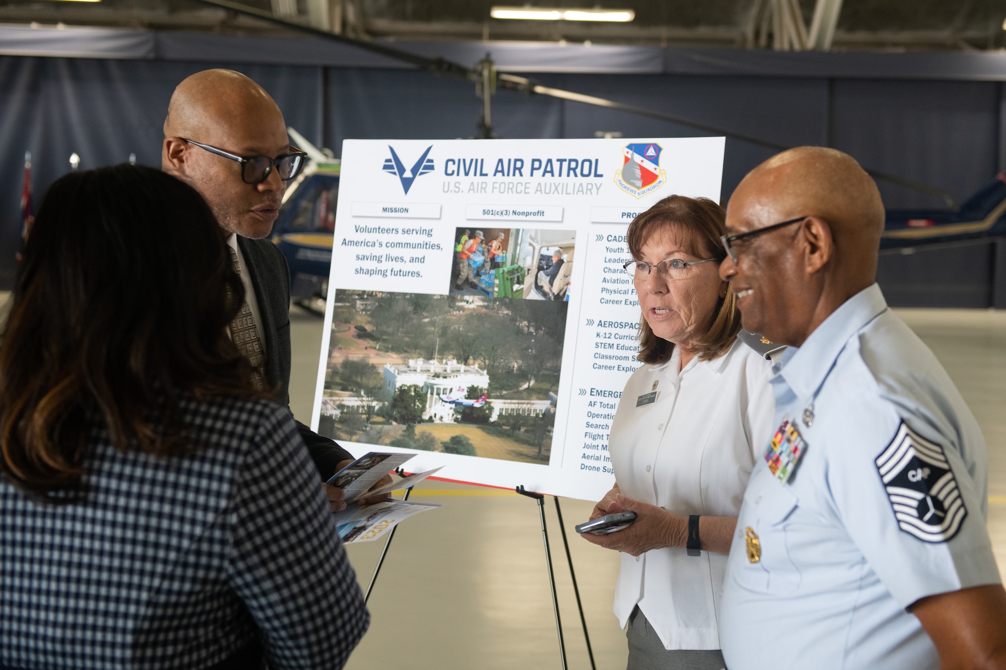 A woman in a uniform speaks with a small group of people.