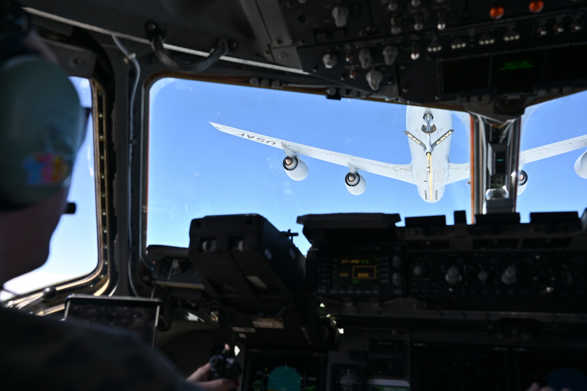 A KC-135 Stratotanker hovers above a C-17 Globemaster as seen through the cockpit window.