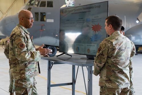 Two Airmen talk to each other about a powerpoint slide show.