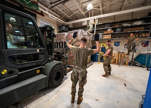 U.S. Air Force Senior Airman Isaac Johnson (left) and Staff Sgt. Lloyd Young (right), from the 133rd Air Transportation Function, move a pallet of humanitarian supplies in St. Paul, April 16, 2023.