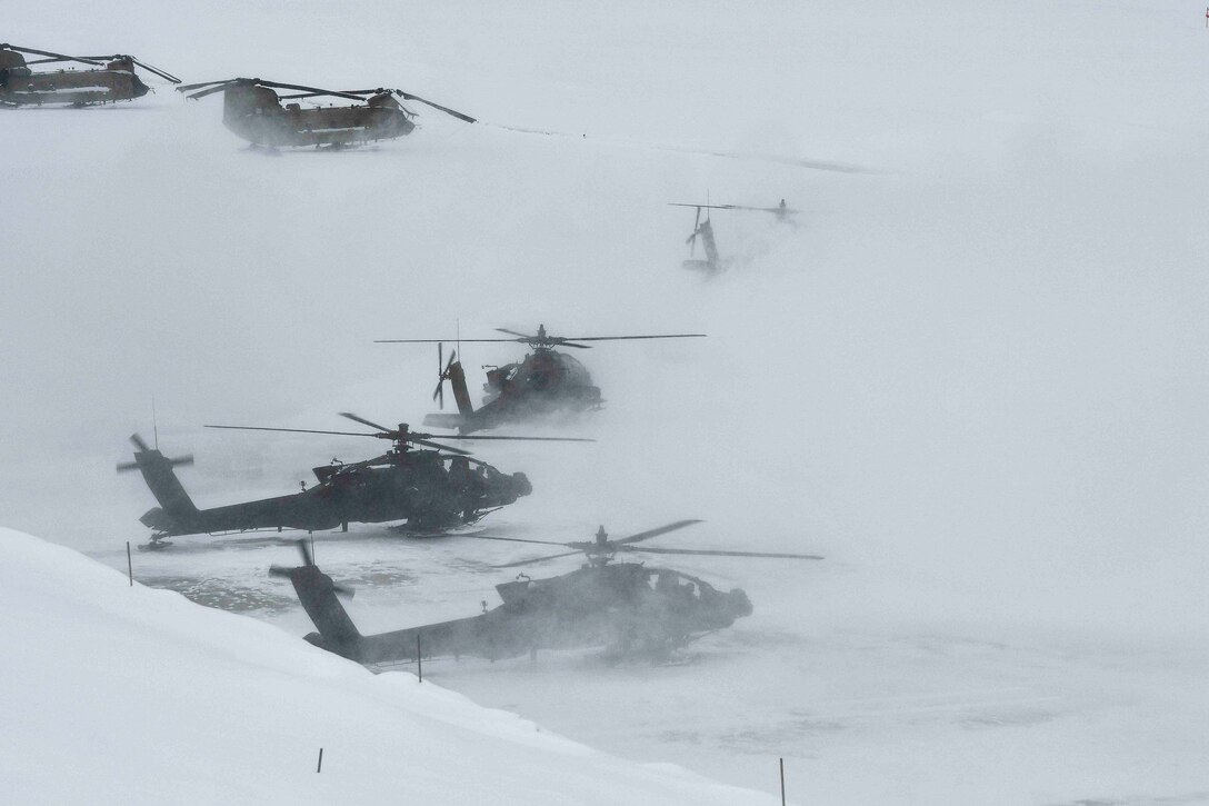 Snow falls on parked military aircraft.