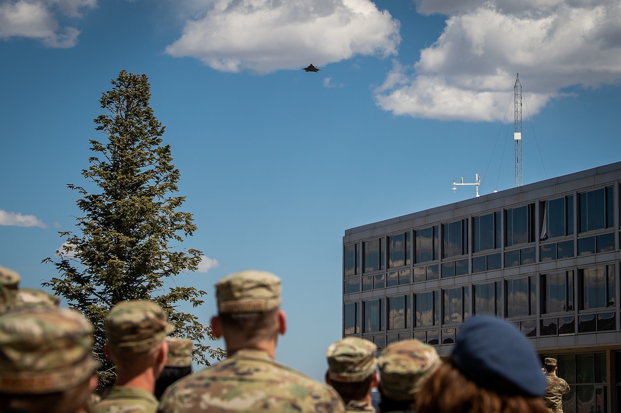 Cadets look up toward the sky as an aircraft flies above.