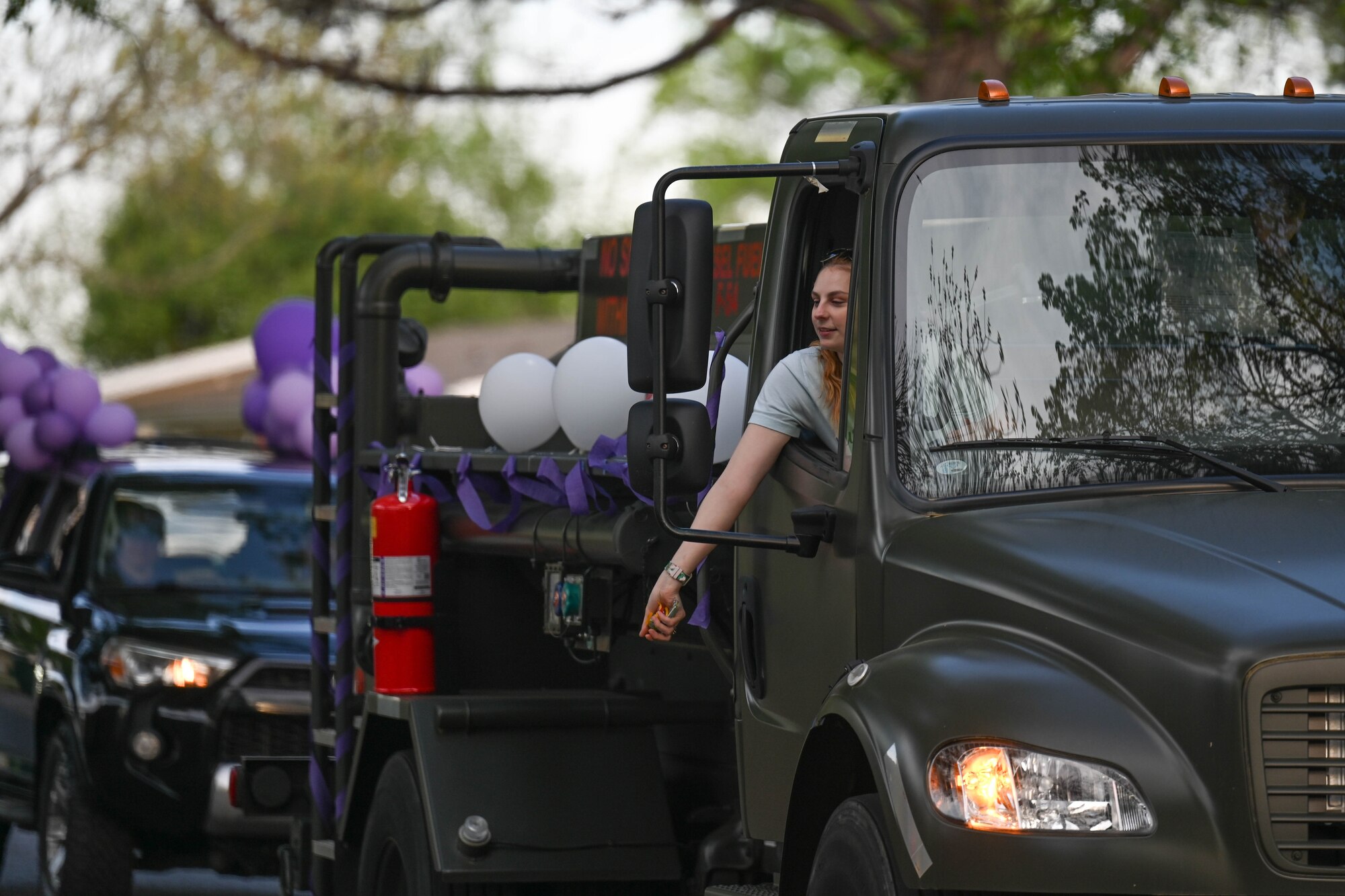 A woman throws candy out of a truck window.