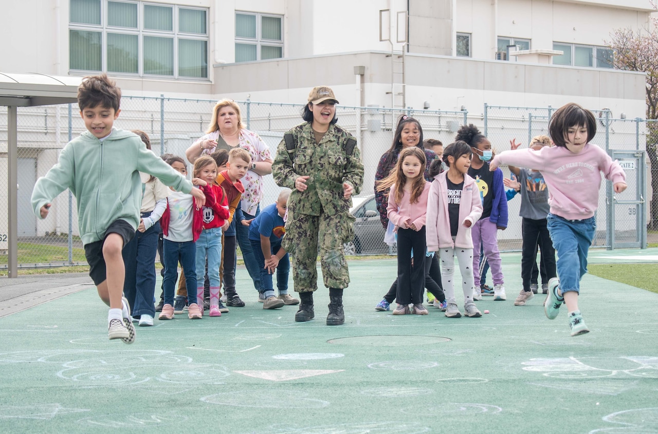 Two students race each other as a sailor watches.