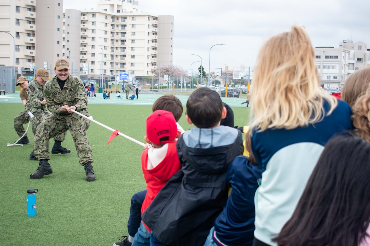 Sailors play tug-of-war with students.