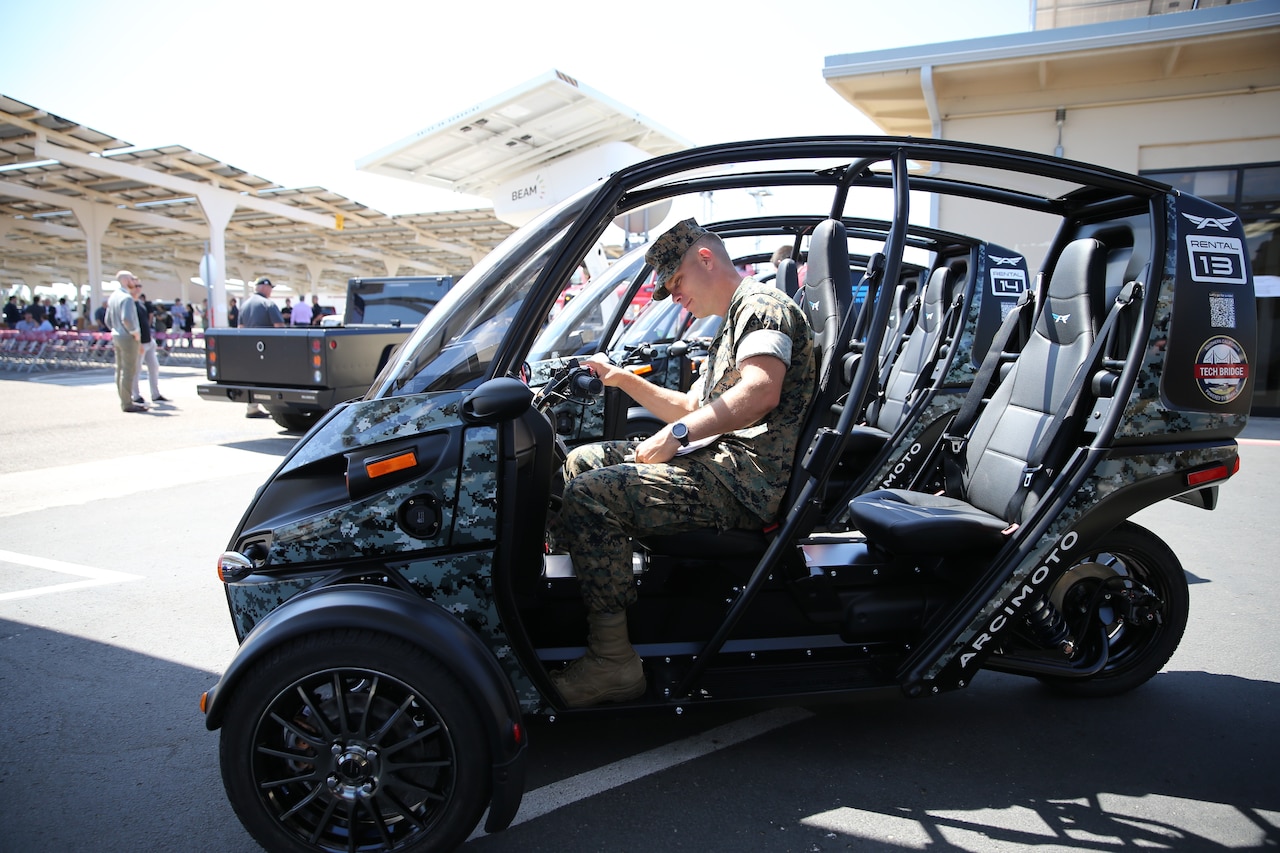 A man in military uniform sits in a vehicle.