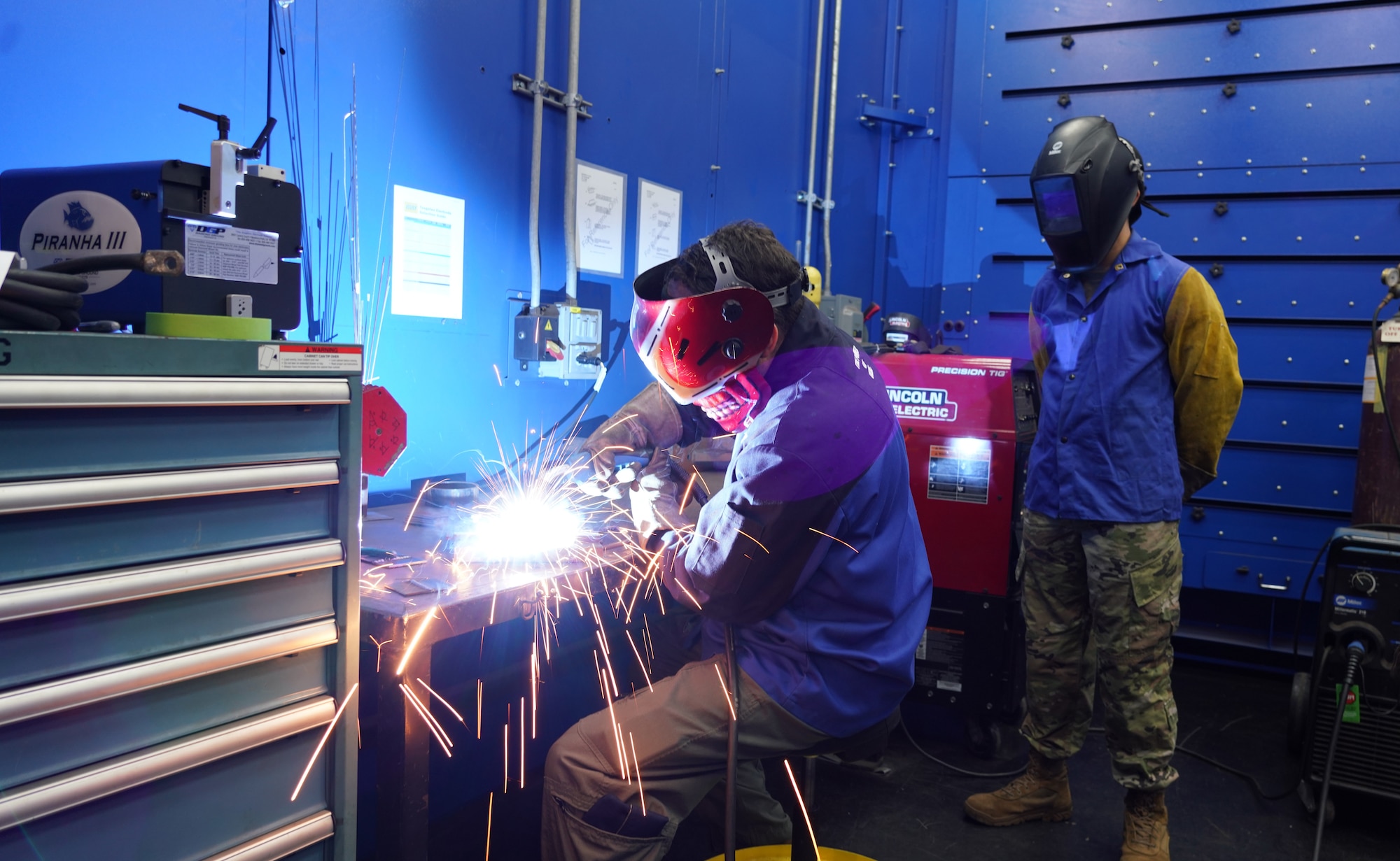 Col. Mattingly welds two pieces of practice metal together with supervision from Senior Airman Defillo.
