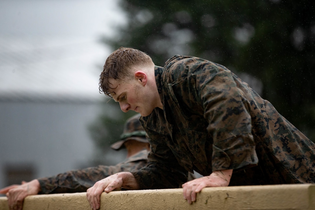 U.S. Marine Corps 2nd Lt. Steven Eckenberg, officer in charge of the Network Support Section, 1st Marine Logistics Group, and a native of Wheaton, Illinois, climbs over a wall during the 2022 Iron Mike Challenge at The Basic School on Marine Corps Base Quantico, Virginia, May 7, 2022.  Competitors from across the Marine Corps covered a distance of 20 miles, completing multiple physical and core skills challenges along the way. (U.S. Marine Corps photo by Cpl. Kedrick Schumacher)