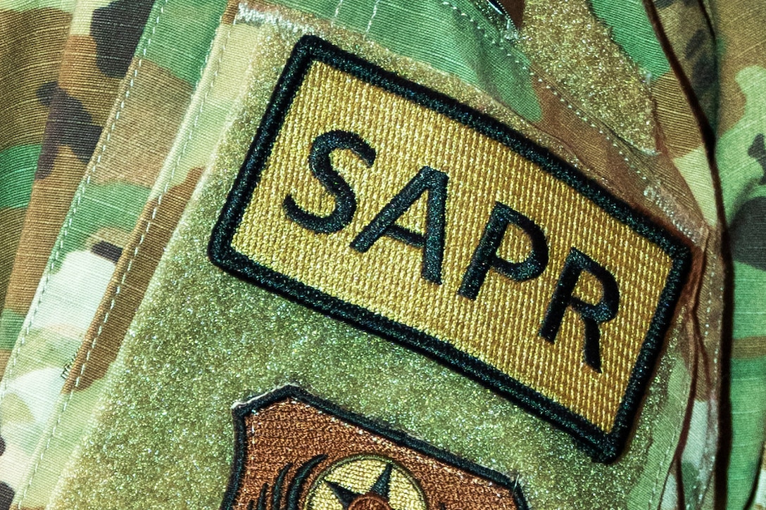 Close-up of badge that says "SAPR" on the arm of a service member's camouflage uniform.