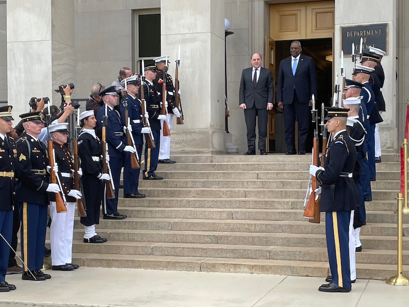 Two men stand at top of steps between two lines of service members.