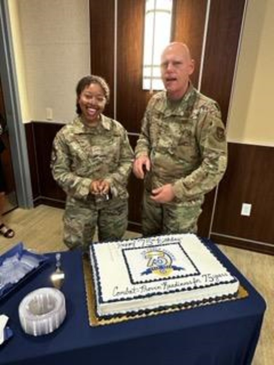 Photo of Maj. Gen. Kemble and Senior Airman Nia Glover posing for pictures after cutting the cake.