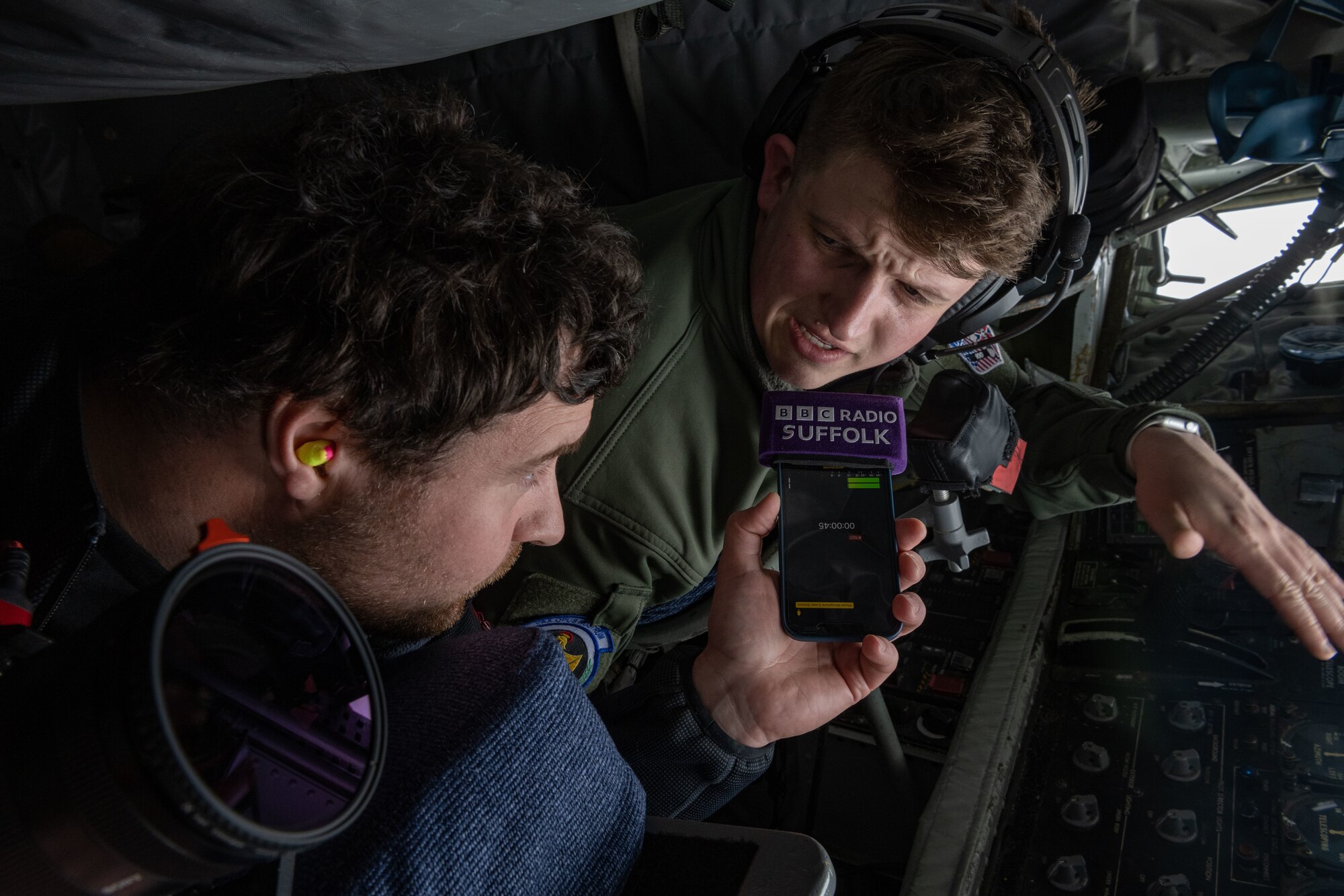 Stuart Howells, left, BBC Radio Suffolk journalist, interviews U.S. Air Force Airman 1st Class Max Richards, 351st Air Refueling Squadron boom operator, about air refueling during a media flight over England