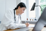 A doctor writes notes at her desk