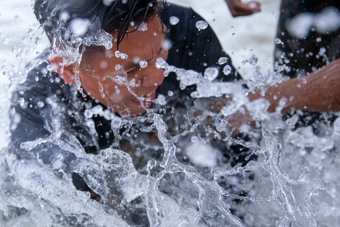 A Marine seen through a large splash of water.