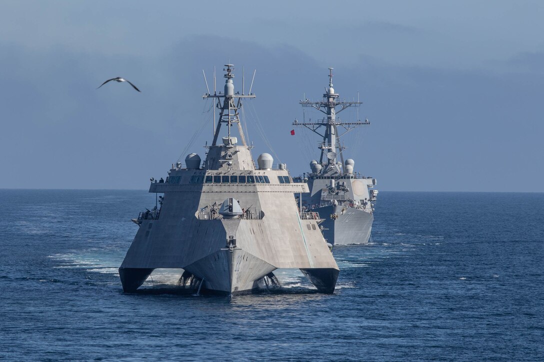Two Navy ships sail in open water.