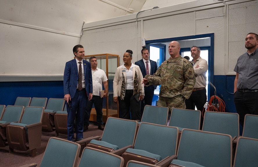 Congressman, Air Force military commander, and senior leadership stand inside an auditorium.