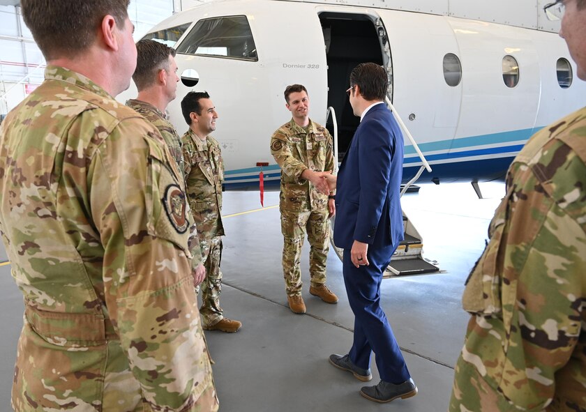 Congressman shakes hand with an Airman in front of a C-146A Wolfhound. Other Airmen also stand around in the hangar as he is greeted.
