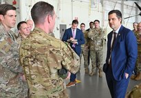 Airman stand around a congressman and engage in conversation in a C-146A Wolfhound hangar