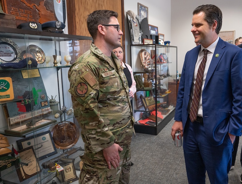 Congressman and military commander have a conversation inside a conference room with glass showcases filled with travel mementos
