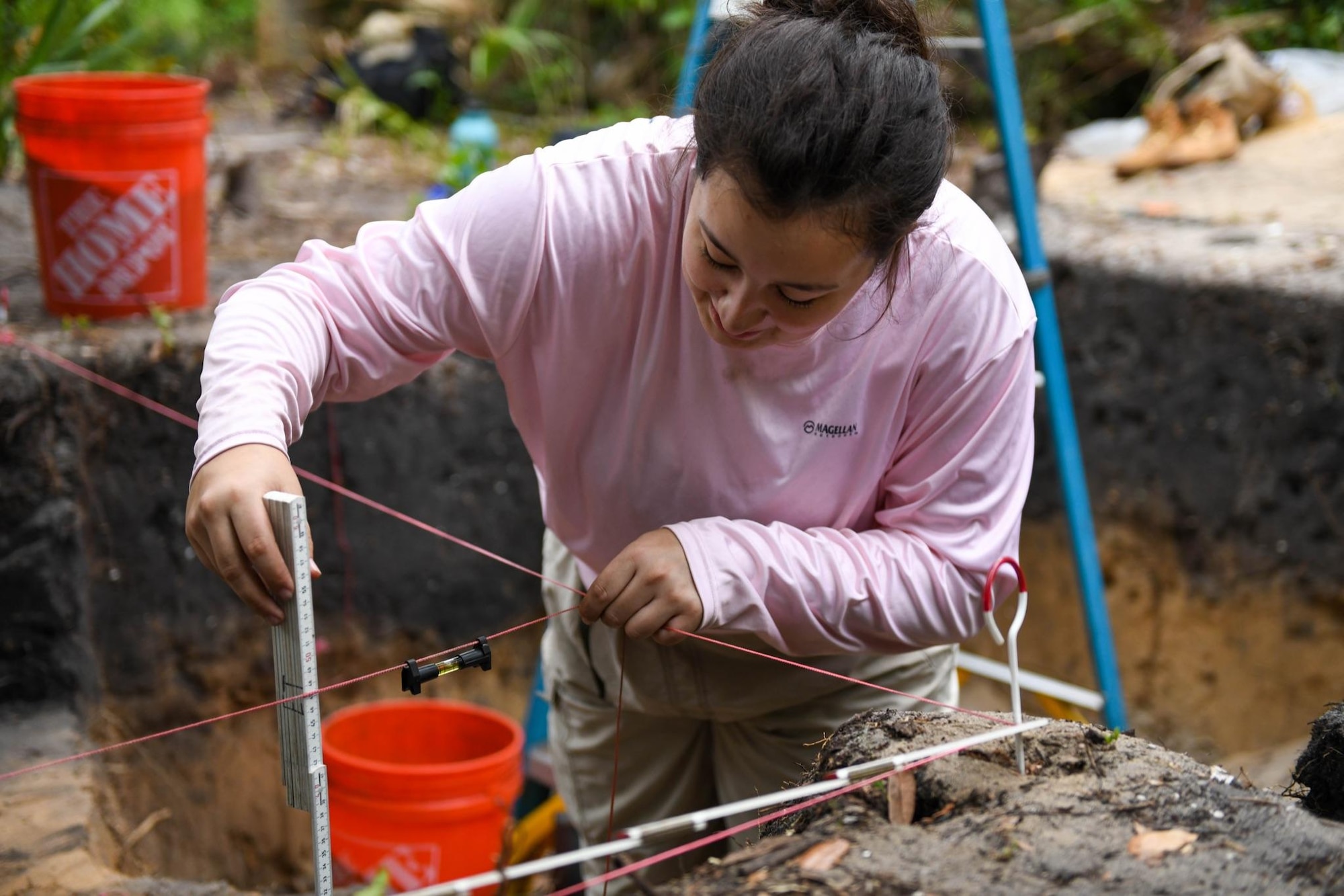 Anya Schmieder, Department of Anthropology student at University of Central Florida, uses a line level to measure a surface level on April 12, 2023, at Cape Canaveral Space Force Station, Fla. Measuring surface levels allow archeologists to determine the approximate time period they are excavating at. (U.S. Space Force photo by Senior Airman Samuel Becker)